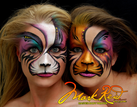 two women with their faces close to each others and complimentary hairstyles that flow away from each other in tiger face paint
